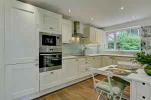 蒂弗顿Pippins的厨房配有白色橱柜和桌椅