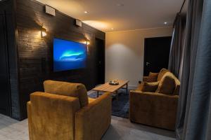 罗瓦涅米Royal Roi Apartments的客厅配有两把椅子和墙上的电视