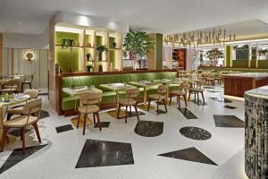 伦敦伦敦希尔顿花园弄酒店的一间带桌椅和绿色墙壁的餐厅
