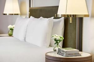 伦敦伦敦希尔顿花园弄酒店的一张带白色枕头的床和一张带书籍的桌子