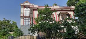 大诺伊达Balaji Guest House - Home Stay的粉红色的房子,前面有栅栏