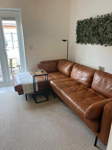 马斯顿格林Modern 2 Bed house - HS2, NEC & Birmingham Airport的客厅里一张棕色的皮沙发,配有桌子