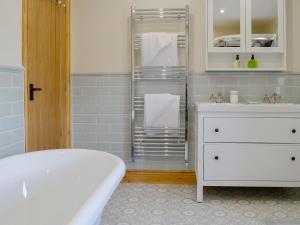 PlumblandHolmegarth的带浴缸和白色梳妆台及毛巾的浴室