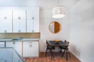 特拉维夫Charming 2BR by HolyGuest的厨房配有白色橱柜、桌子和镜子