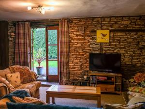 Llangattock Lingoed基利农舍乡村别墅的一间带电视和石墙的客厅