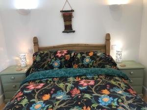 金尤西The Old School, Kingussie的一间卧室配有一张带花卉床罩和2个床头柜的床。