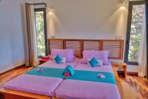 贝岛ANJARA LODGE Villa de 3 chambres的一间卧室配有一张带紫色枕头的大床