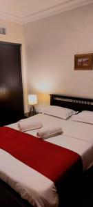 安曼Tamrah Suites Hotel的一间卧室配有两张红色和白色床单