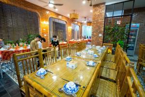顺化Tâm Family Homestay-Huế的一间设有木桌的餐厅,有人站在房间里