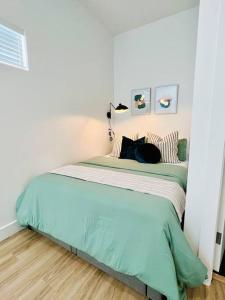 奥克兰Fully-Stocked Studio Suite的白色卧室配有带绿色床单的床