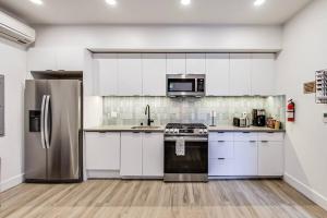 奥克兰Fully-Stocked Studio Suite的厨房配有白色橱柜和不锈钢用具