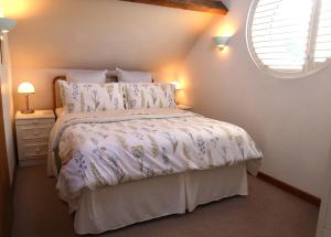 克努斯福德Charming 2-Bed Cottage in Toft Knutsford的卧室配有一张带白色棉被的床和窗户。