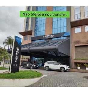 瓜鲁柳斯Flat Guarulhos的停在大楼前停车场的汽车