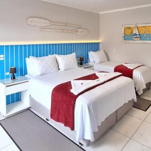 纳韦甘蒂斯NAVEGA PRAIA HOTEL的蓝色和白色的客房内的两张床