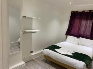 伦敦W3 Guest House的一间卧室配有一张带窗户和镜子的床