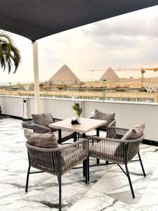 开罗Peace Inn West Pyramids Cairo的庭院配有桌椅,后面设有金字塔