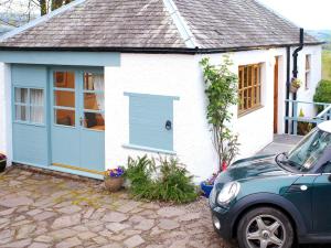 MuthillThe Wee House的白色的小房子,设有蓝色车库