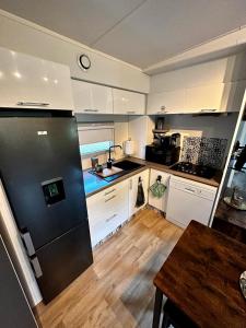 勒格劳德阿格德Mobil home 3 chambres avec jacuzzi的厨房配有白色橱柜和黑色冰箱。
