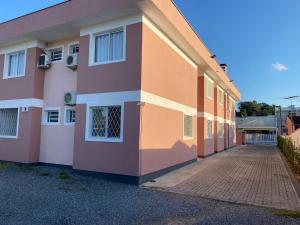 约恩维利EDIFÍCIO KARINE - STUDIO n⁰ 04的一座橙色粉红色的建筑,有砖车道