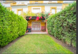 伊斯兰蒂拉Adosado en Islantilla的一座房子,有一座带门和灌木的院子