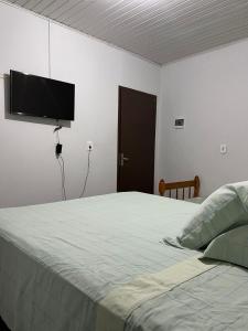 帕罗卡Residencial Coração do Mar的卧室配有一张壁挂式平面电视的床。