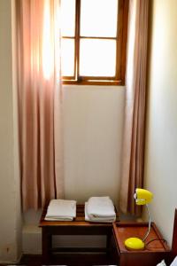 阿雷基帕Maison verte - Guest House的一间设有一张桌子、一个窗口和一个黄色灯的房间