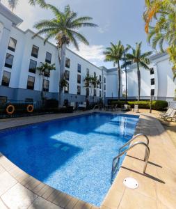 阿拉胡埃拉Hampton By Hilton San Jose Airport Costa Rica的棕榈树建筑前的游泳池