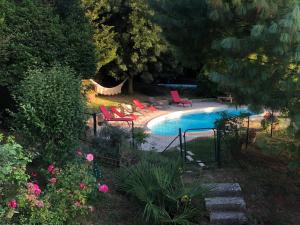 FanjeauxGîte Au Coeur Du Pays Cathare的庭院旁的游泳池,配有红色椅子