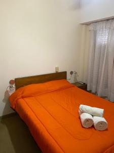 内科切阿Nueva Hostería Rio Colorado Necochea的一间卧室配有橙色床和2条毛巾