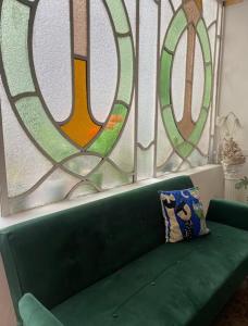 科尔多瓦Rivière Hostel的三扇彩色玻璃窗前的绿色沙发