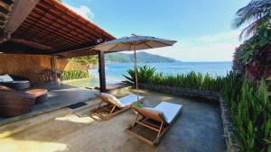 阿拉夏奇巴海滩Casa da Ilha的一个带椅子和遮阳伞的庭院和大海
