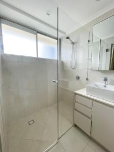 黄金海岸拜伦内公寓的一间带玻璃淋浴和水槽的浴室