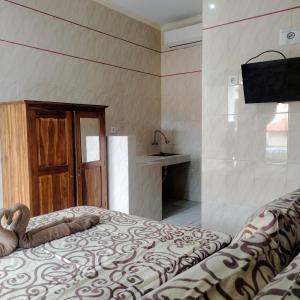勒吉安Santhi Graha by NauliTabitha的一间卧室配有一张床,墙上配有电视