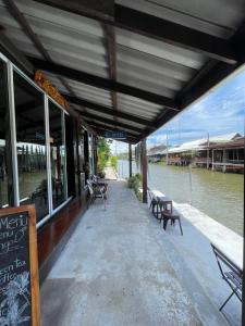 RatchaburiReuan Vilawan的水边码头上一家带桌椅的餐厅