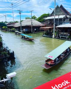 RatchaburiReuan Vilawan的两艘船在建筑物旁边的一条河里