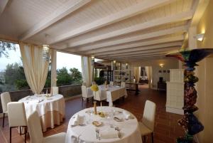 SaludecioLocanda Belvedere的餐厅设有白色的桌椅和窗户。