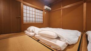 中津川市GUESTHOUSE YANAGIYA的一间卧室配有一张带白色床单的床和一扇窗户。