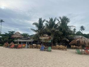 苏梅岛Paradise Bungalows Lamai Beach的棕榈树海滩,海滩上摆放着桌椅