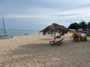 苏梅岛Paradise Bungalows Lamai Beach的一个带桌椅和草伞的海滩