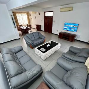 达累斯萨拉姆En-Suite Rooms W/Pool & Gym in Mikocheni Near Beach的带沙发、桌子和电视的客厅