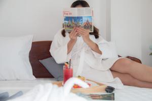 金边White Corner Hotel的坐在床上读杂志的女人