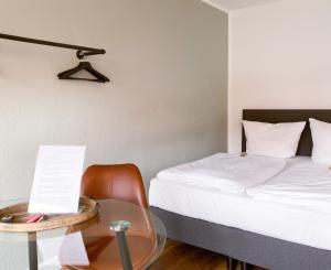诺伊斯Apartment Neuss-Düsseldorf Messe的一间卧室配有一张床和一张玻璃桌及椅子