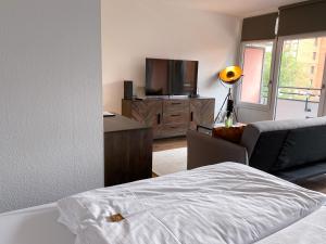 诺伊斯Apartment Neuss-Düsseldorf Messe的一间卧室配有一张床、一台电视和一张沙发