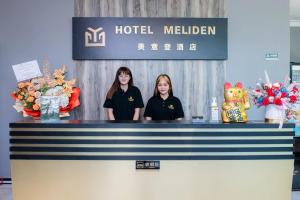 山打根Hotel Meliden的两个女孩站在旅馆里的一个柜台后面