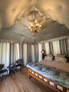 新德里Chitragarh Farm的配有吊灯的帐篷内一间卧室,配有一张床