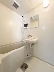 Hanabatachōエスポアール新町Ⅵ(101)的白色的浴室设有水槽、浴缸和水槽。