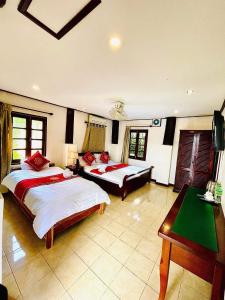 琅勃拉邦Vieng Savanh II Hotel的一间卧室设有两张床和一张绿桌