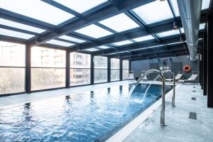 米兰米兰丽笙酒店的一个带窗户的大型室内游泳池和一个大型游泳池
