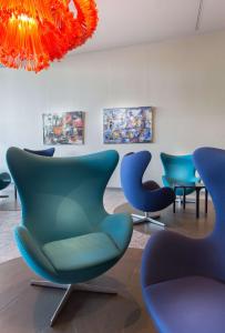 克洛滕Radisson Blu Hotel Zurich Airport的一间设有蓝色椅子和吊灯的等候室