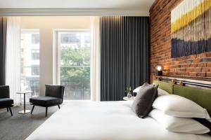 西雅图The Alexis Royal Sonesta Hotel Seattle的卧室配有白色的床和砖墙